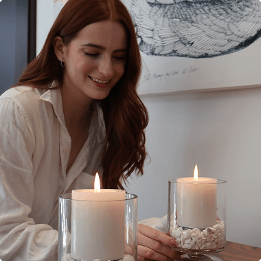 Una mujer pelirroja sonriendo delante de una vela encendida